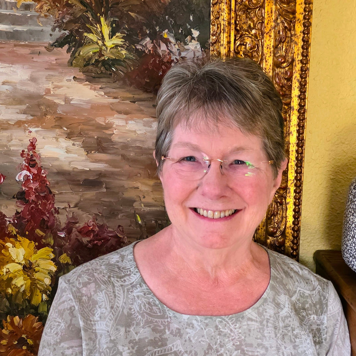 picture of woman with short brown hair in front of painting